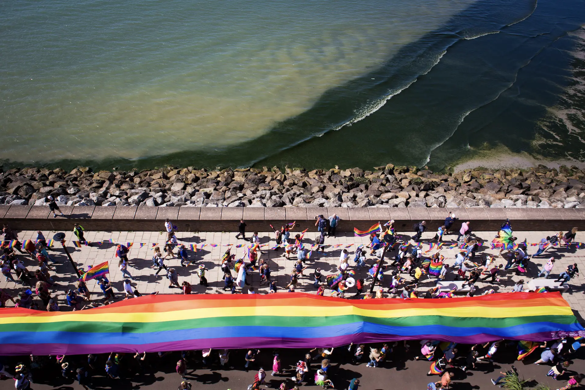 Aerial view of the Pride parade and rainbow flag on the seafront in Jersey